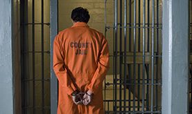 Man in orange jumpsuit walking into cell waiting for bail bondsmen in Harris County