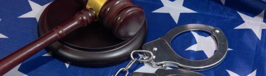 A gavel and handcuffs on an American flag that were part of trial where All About Bail Bonds helped the defendant post bail