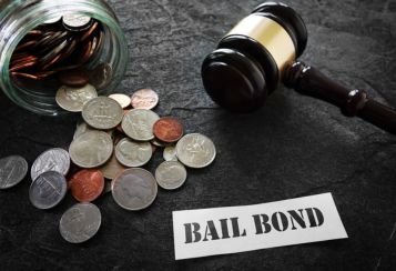 A bail bond card, gavel and jar of spilled coins