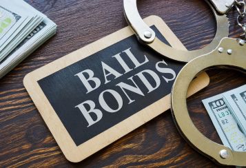 a bail bonds card, handcuffs and cash sitting on a desk
