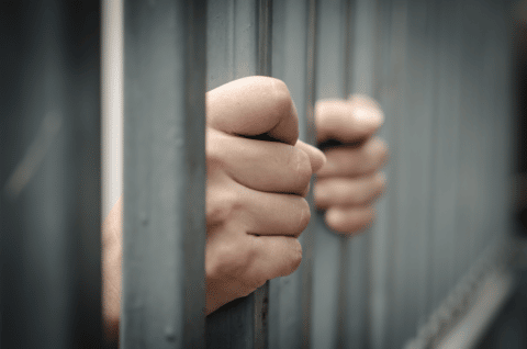 Hand gripping jail bars waiting for a local bail bondsman in Pasadena