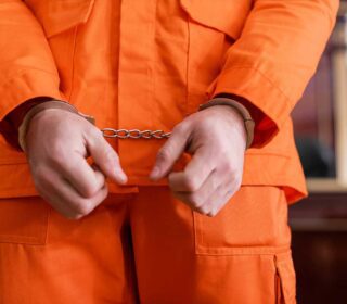Handcuffed inmate in orange jumpsuit needing a local bail bond in Spring