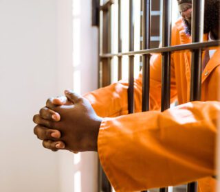 Inmate's hands through jail bars waiting for bail in Lazybrook
